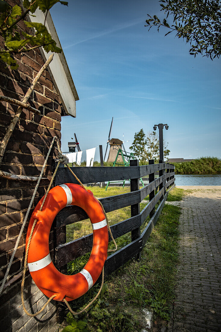 Rettungsring am Zaun mit Windmühlen im Hintergrund, Niederlande