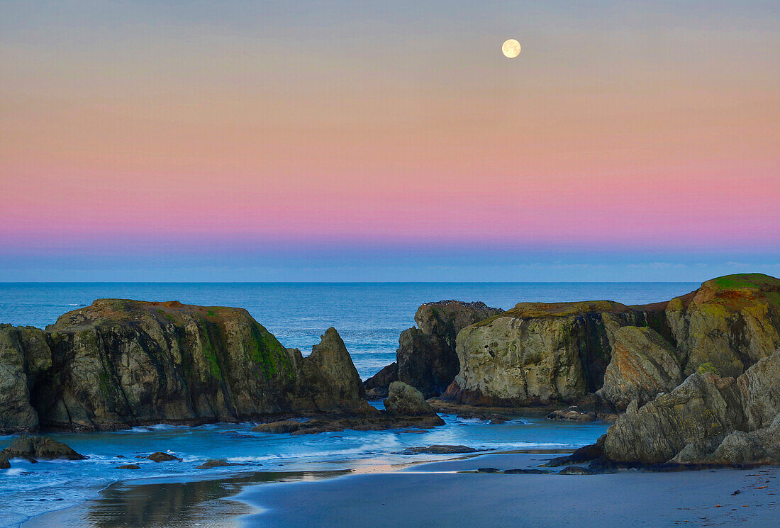 USA, Oregon, Bandon. Vollmond geht über Seestapel am Strand unter