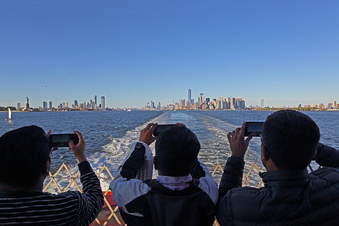 Staten Island Ferry passengers take photos of the Manhattan Financial District skyline, New York, New York, USA