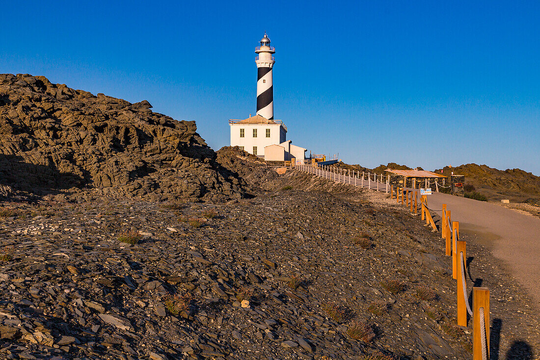 The narrow road to the lighthouse at Cape Favàritx amid dark slate rock, Menorca, Spain