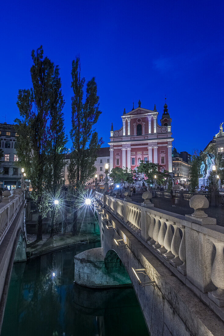 Ljubljana Castle at night, with the triple bridge in foreground.