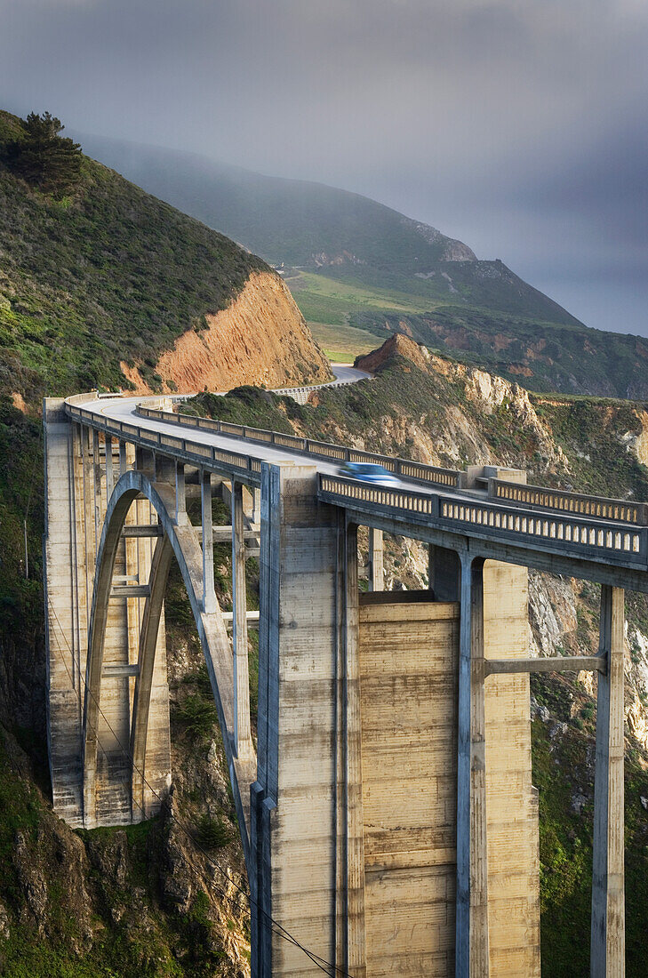 Ein Auto auf einer Brücke an der Pazifikküste von Big Sur, Berge und Nebel.