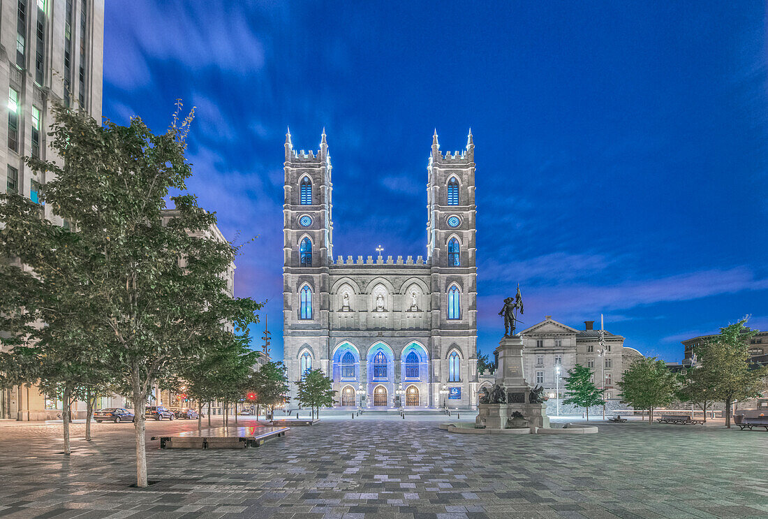 Die Notre-Dame-Basilika, beleuchtet in der Abenddämmerung auf dem Stadtplatz in der Altstadt von Montreal.