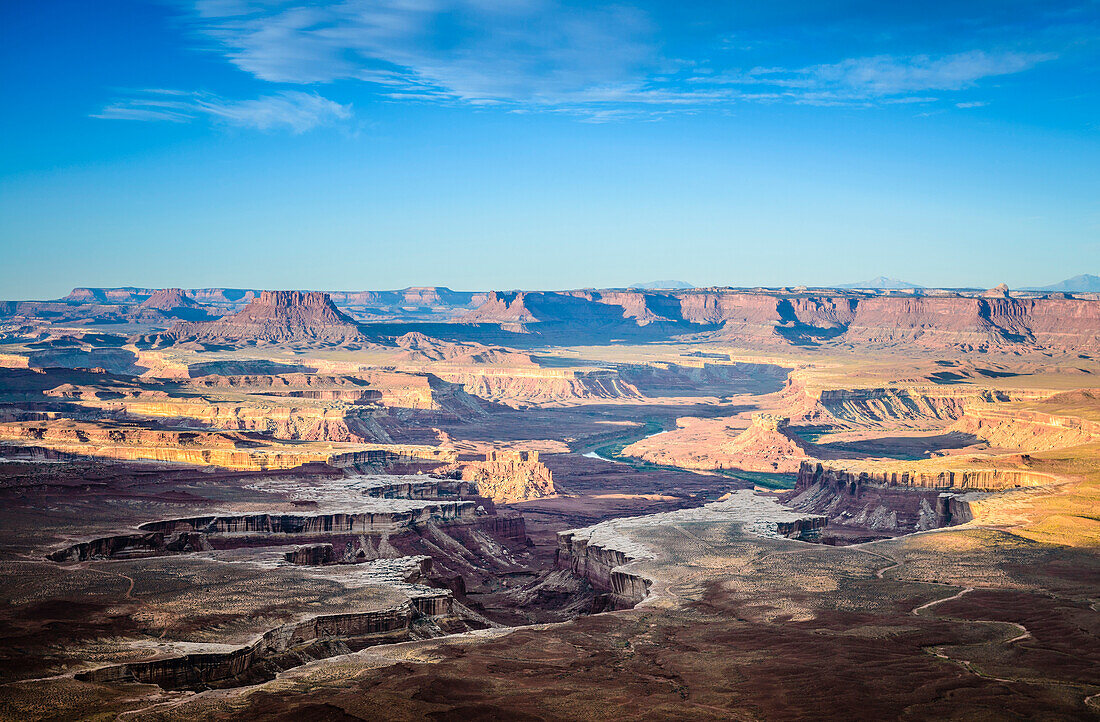 Views across the canyons of the Canyonland National Park at sunset, sandstone ridges and cliffs and the Colorado River.