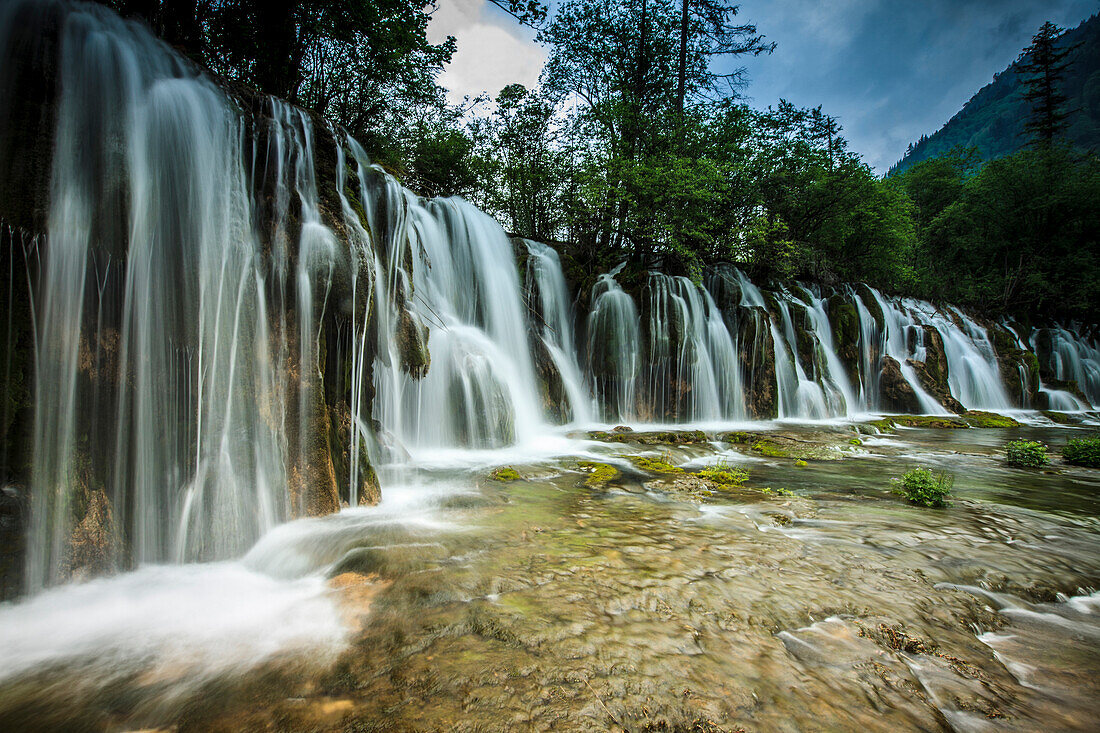 Wasserkaskaden über Felsen im Nationalpark, UNESCO-Weltkulturerbe, Jiuzhaigou-Wasserfall, Sichuan, China