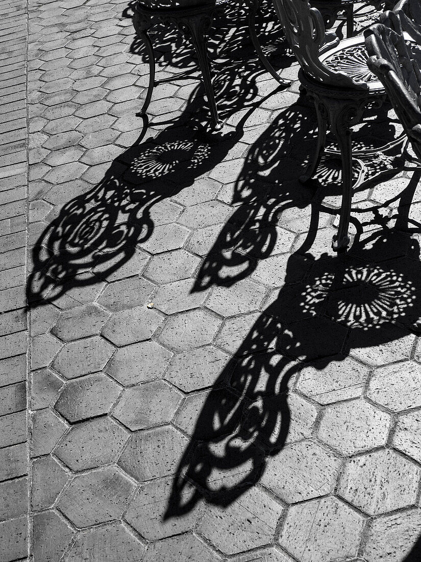 USA, Pennsylvanien. Schmiedeeiserne Stühle und Schatten auf einer Terrasse an einem sonnigen Tag.