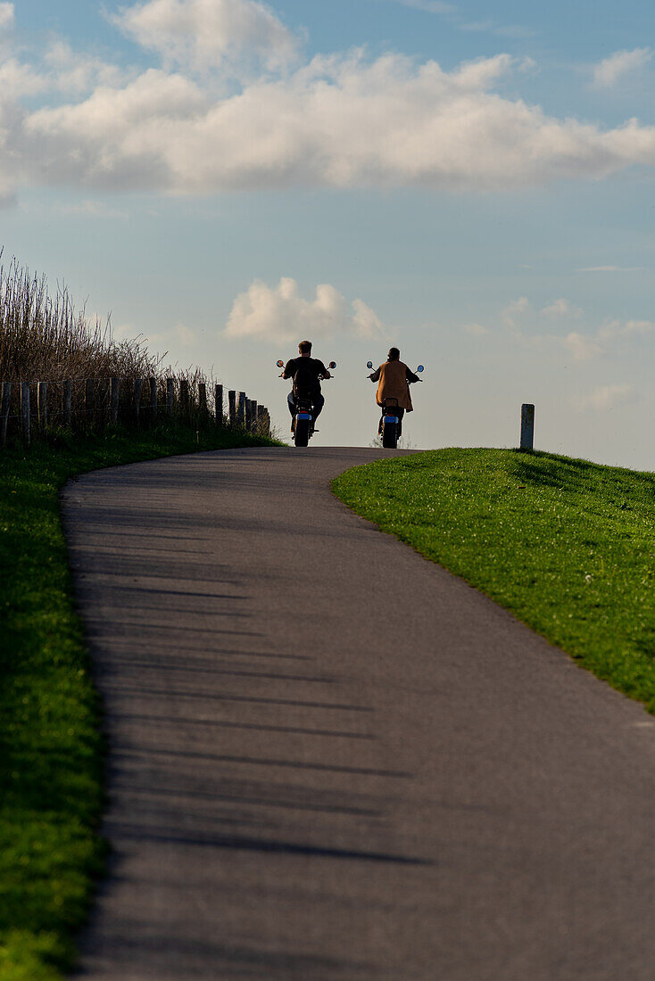 A couple on a electric motorcycle enjoying a ride near the seaside.