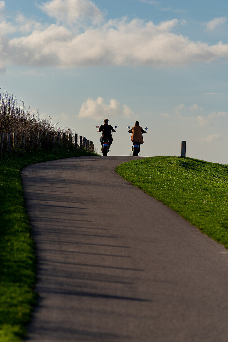 Ein Paar auf einem Motorrad, das eine Fahrt in der Nähe des Meeres genießt, Niederlande