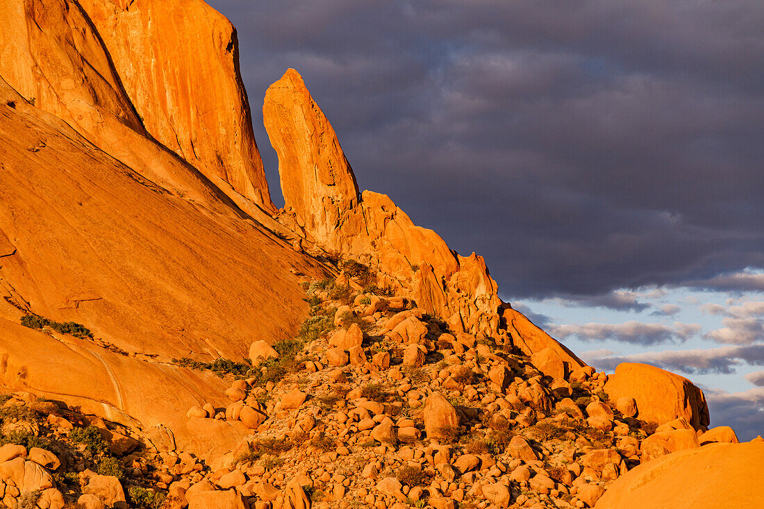 Striking red rocks against dark clouds on Mount Spitzkoppe, the Matterhorn of Namibia, Africa