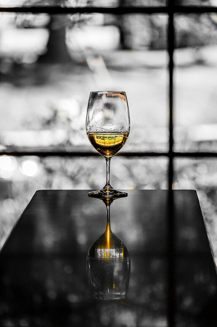USA, Staat Washington, Woodinville. Ein Glas Weißwein spiegelt einen Frühlingstag in einem Weingut in Woodinville wider.