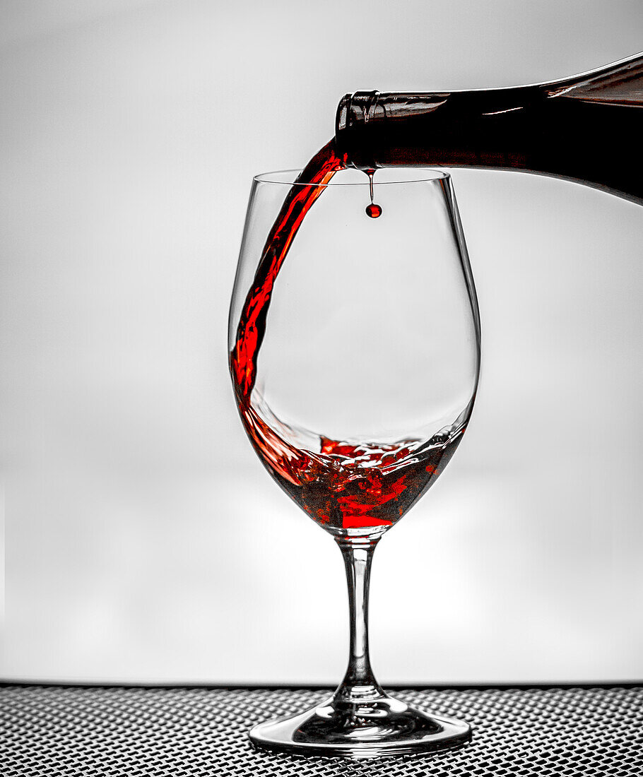 USA, Staat Washington, Spokane. In ein Weinglas gegossener Rotwein erzeugt einen perfekten runden Tropfen,