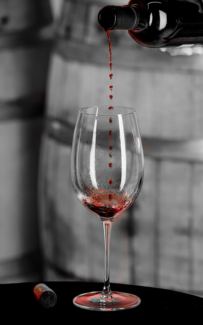 USA, Staat Washington, Woodinville. Einströmender Rotwein wird in der Luft aufgefangen, bevor er das Weinglas berührt.