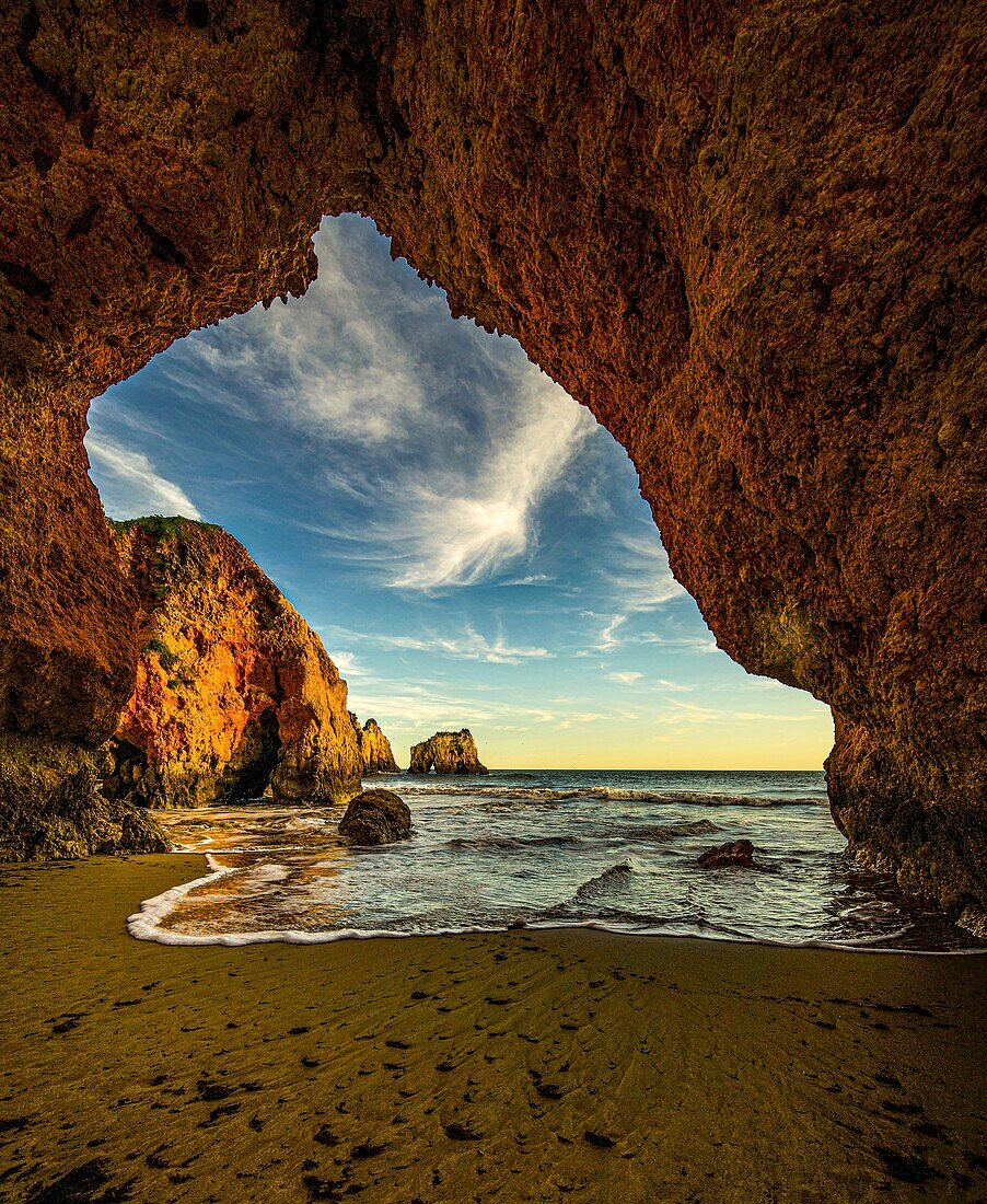 View through a rock arch to the sea, Praia dos três Irmaos, Algarve, Portugal