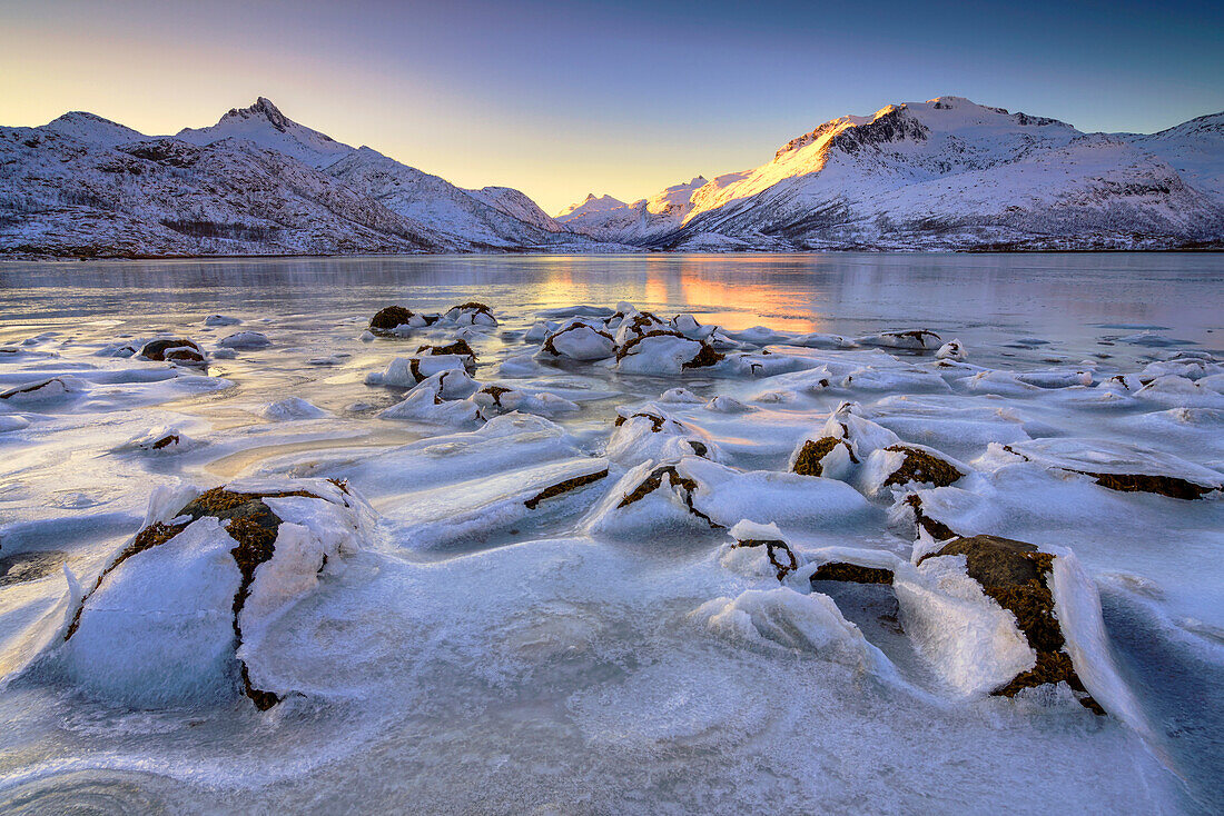 Interesting ice formations, in the background mountains in the evening light in Lofoten, Norway.
