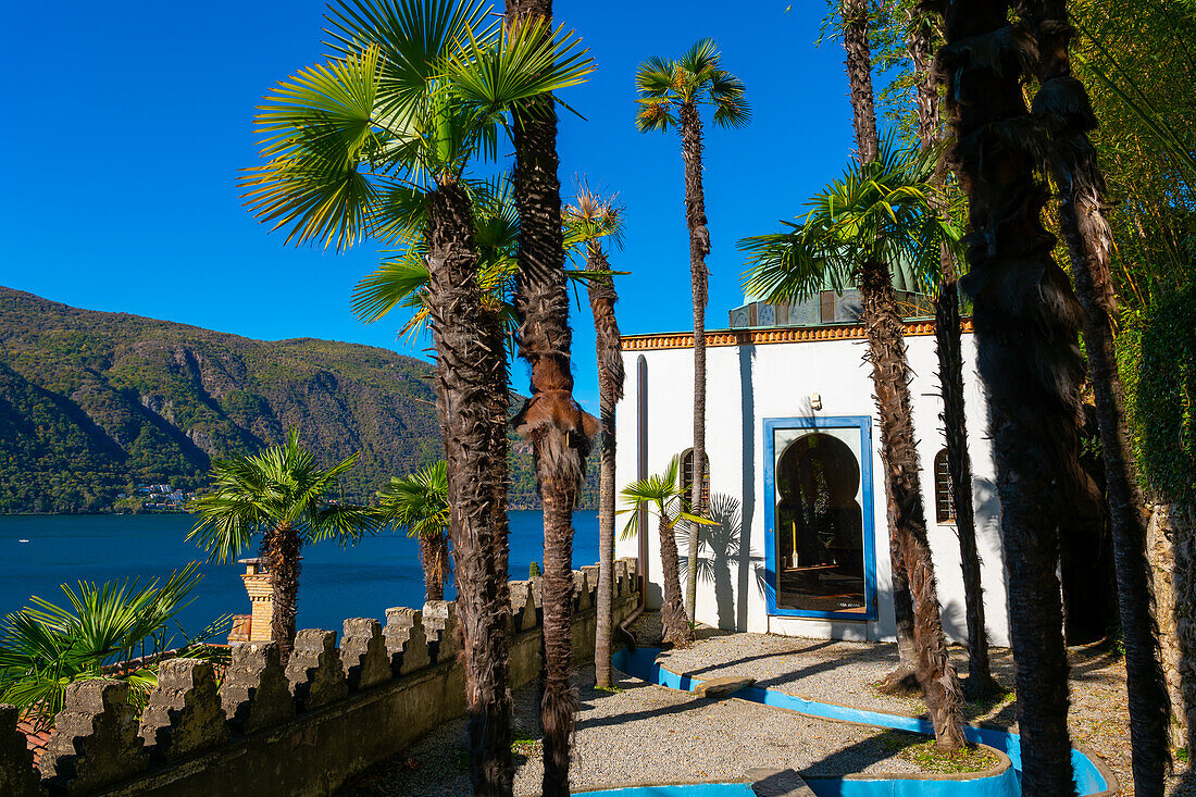Arabic House and Patio with Palm Tree and Sunlight and Lake Lugano with Mountain in Park Scherrer in Morcote, Ticino, switzerland.