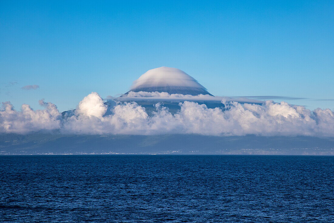 Mount Pico volcano with cloud hat seen from the sea, near Pico island, Azores, Portugal, Europe