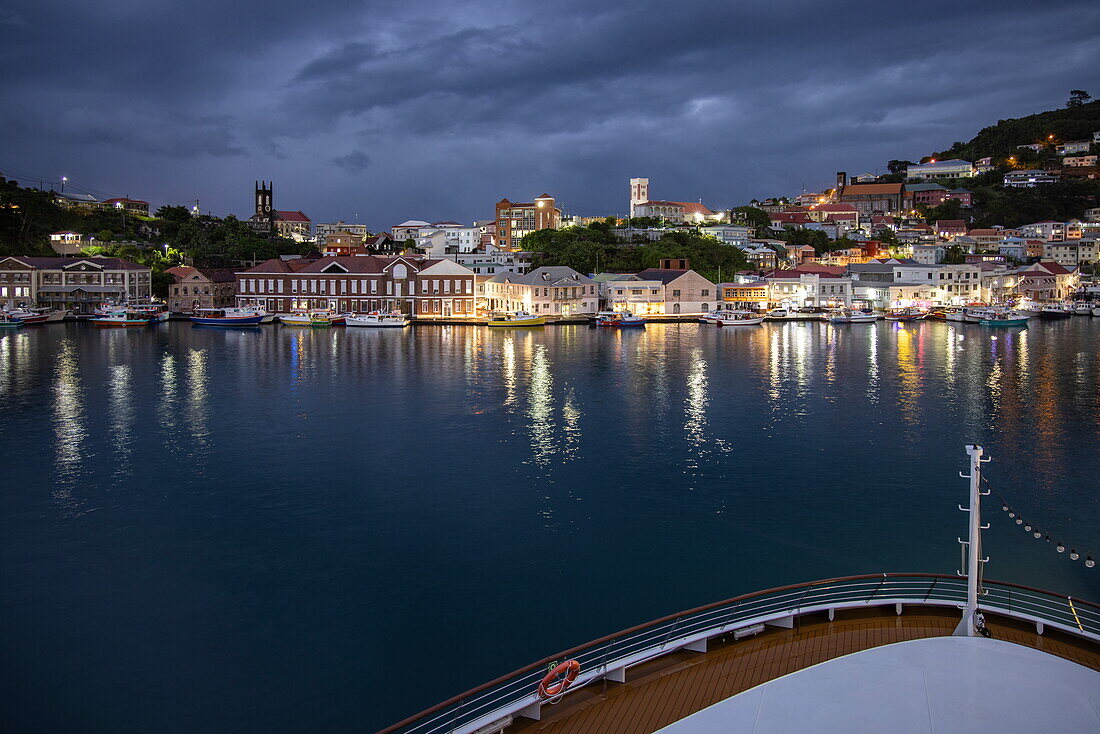 Bow of expedition cruise ship World Voyager (Nicko Cruises) in port overlooking city lights at dusk, St George's, St George, Grenada, Caribbean