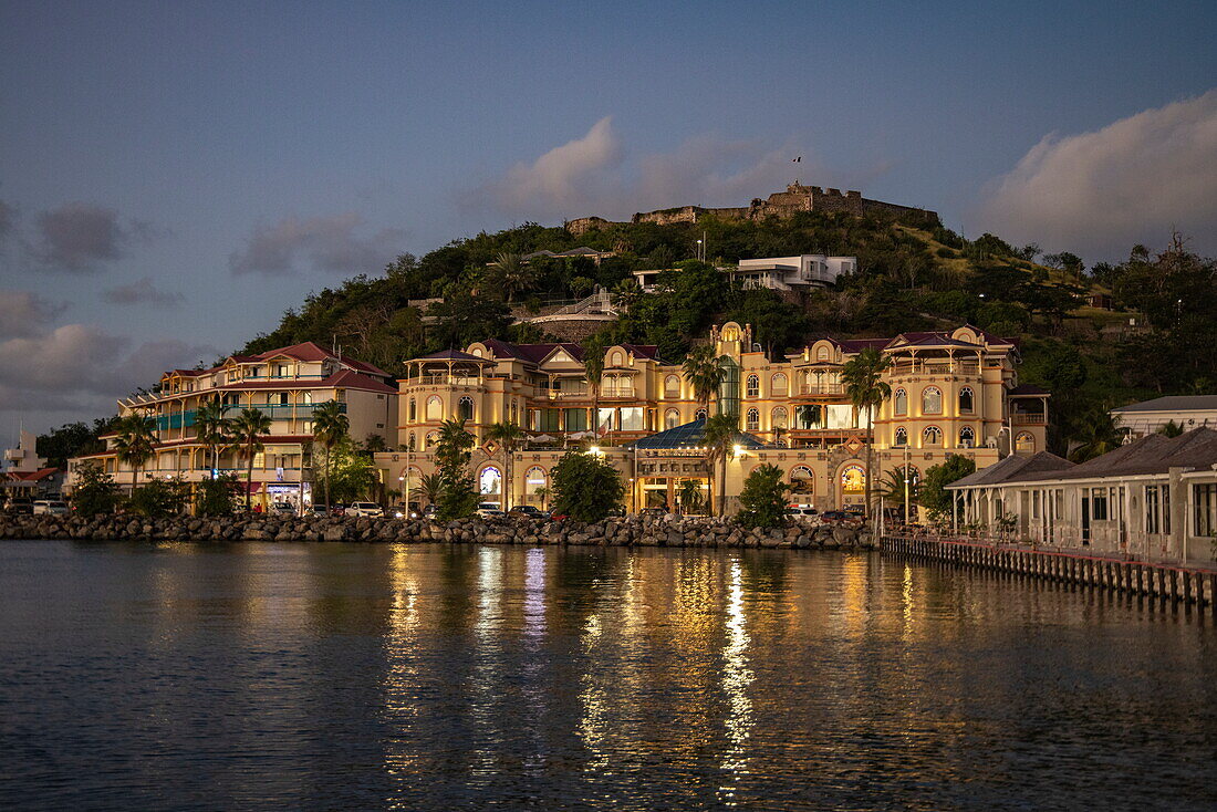 Gebäude am Wasser in der Abenddämmerung mit Fort St.Louis in der Abenddämmerung, Marigot, Saint Martin (Sint Maarten), Karibik