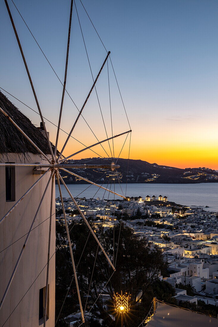 Windmill in front of the 180º Sunset Bar overlooking the town with the famous Mykonos windmills and islands at dusk, Mykonos, South Aegean, Greece, Europe