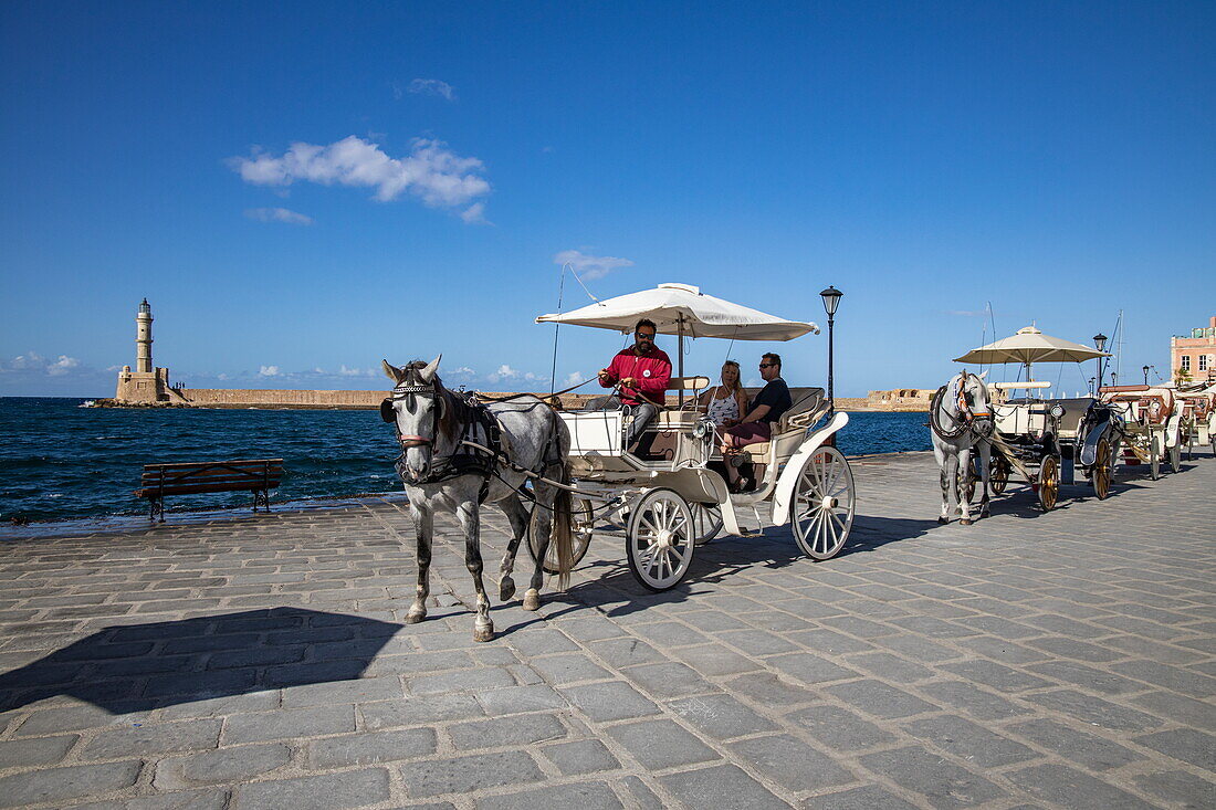 Tourists enjoy a horse and carriage ride along the Venetian Harbour, Chania, Crete, Greece, Europe