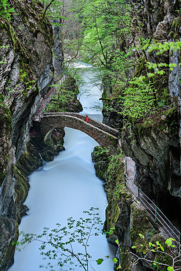 Frau beim Wandern geht auf Steinbrücke über die Areuse, Areuse-Schlucht, Schweizer Jura, Neuenburg, Schweiz