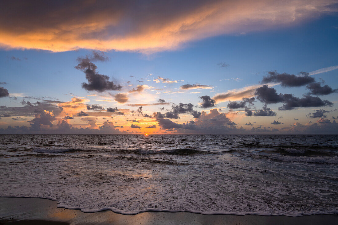 Sonnenaufgangshimmel über Meer und Strand