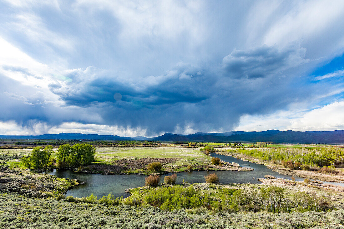 Gewitterwolken über der grünen Wiese mit Bach, Bellevue, Idaho, USA