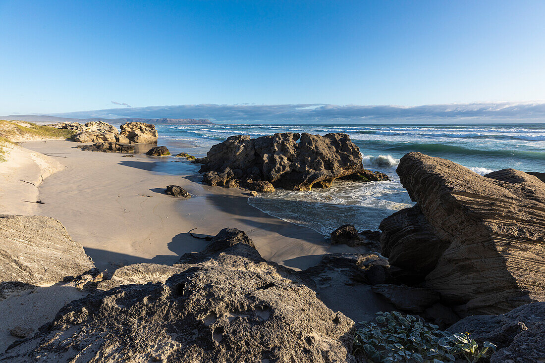 Blick auf Felsformationen und Wellen am Meer, Hermanus, Südafrika