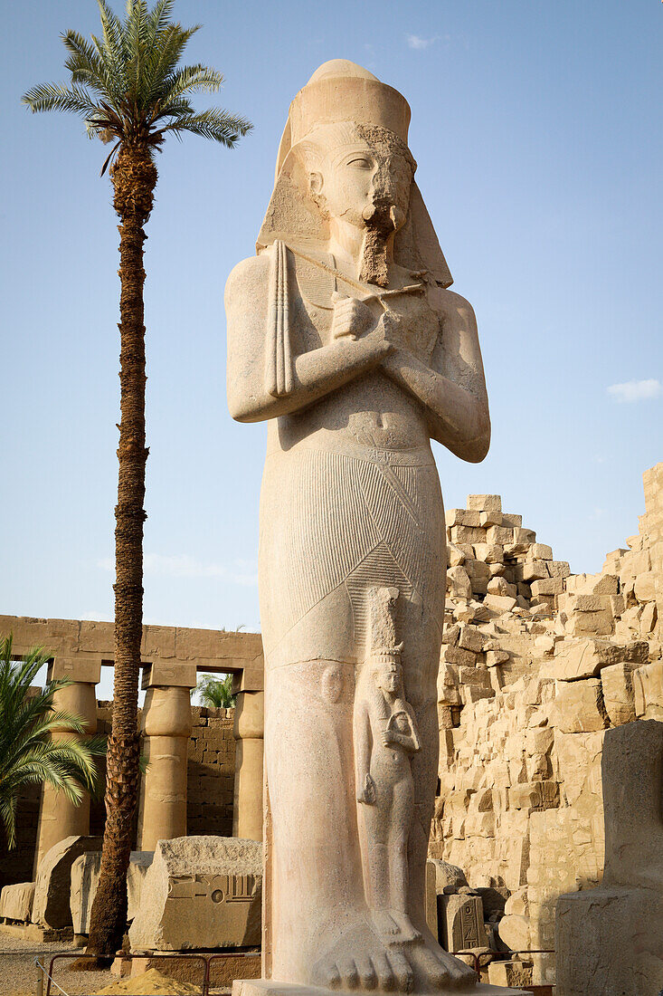Ägypten, Luxor, Pharao-Statue und Palme am Tempel von Karnak