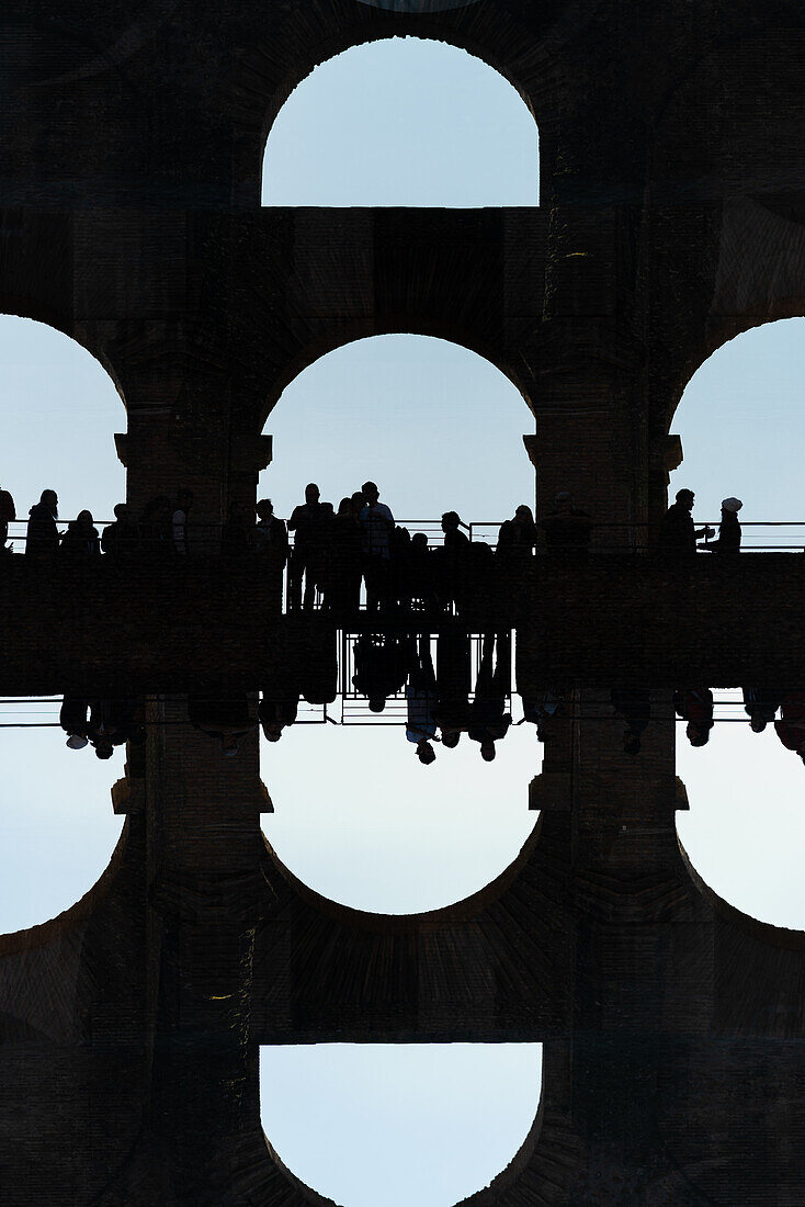 Double exposure of tourist silhouettes seen in the arches of the Colosseum in Rome, Italy.