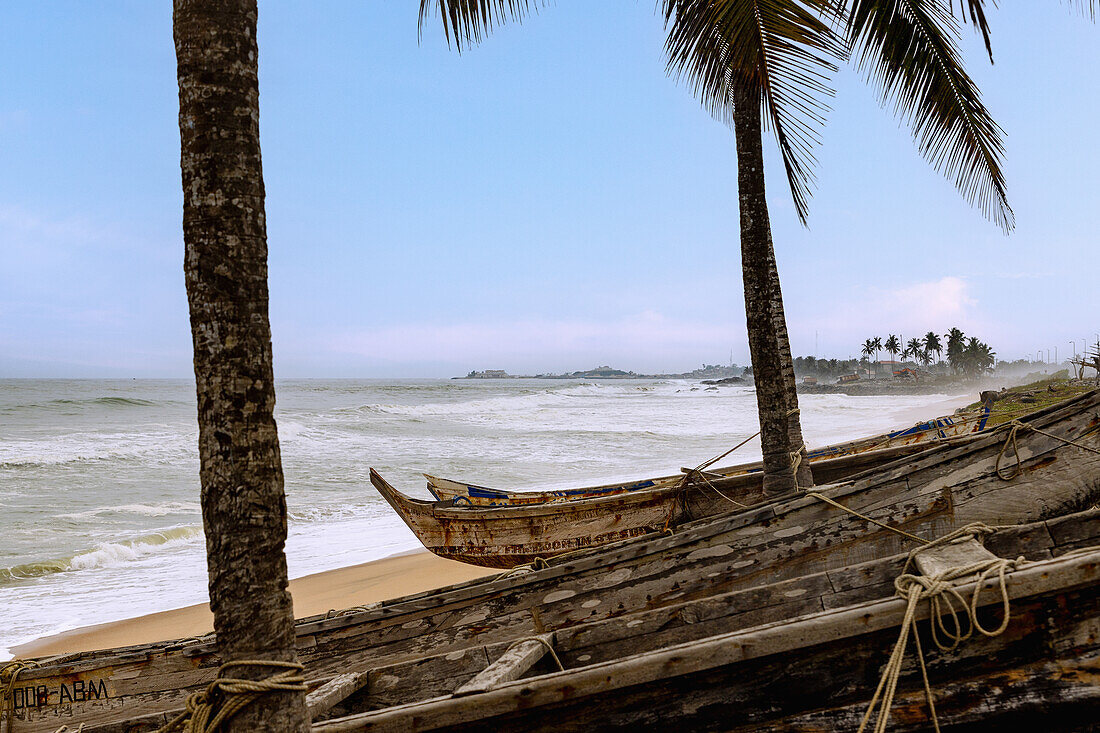 Elmina Beach mit Pirogen und Blick auf Castle in Elmina an der Goldküste in der Central Region im Süden von Ghana in Westafrika