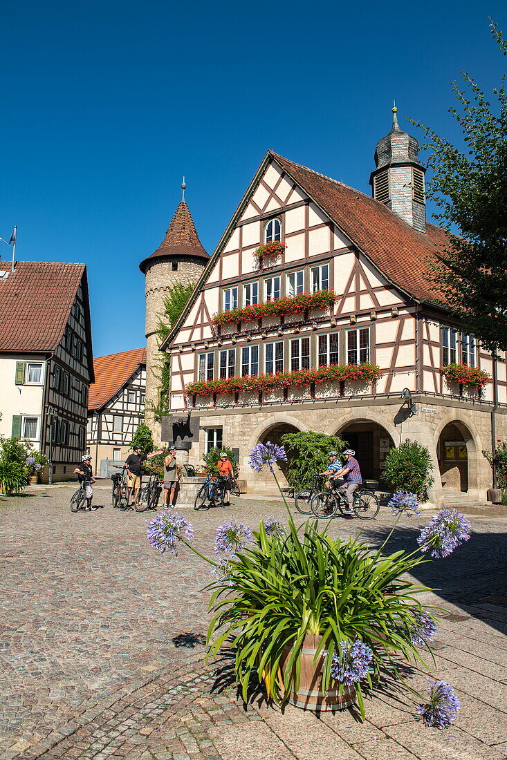 Group of cyclists next to fountain in front of town hall, Niederstetten, Franconia, Baden-Wuerttemberg, Germany, Europe