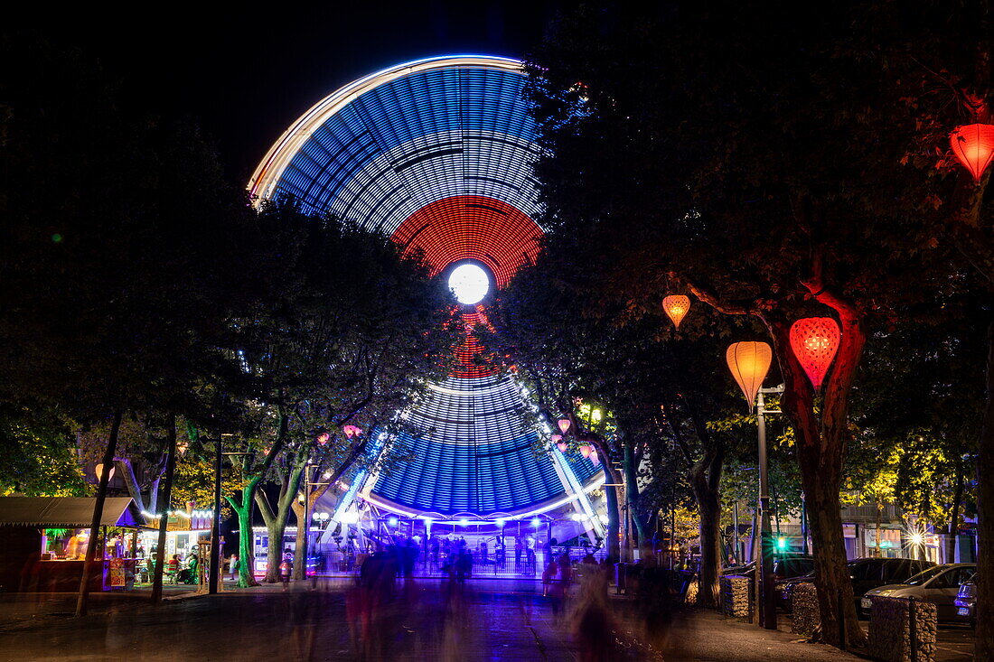 Nachtaufnahme von einem Riesenrad das mit französischen Farben beleuchtet ist, Béziers, Hérault, Frankreich, Europa