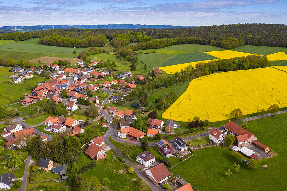 Luftaufnahme des Dorfes mit blühenden gelben Rapsfeldern, Haunetal, Stärklos, Rhön, Hessen, Deutschland, Europa