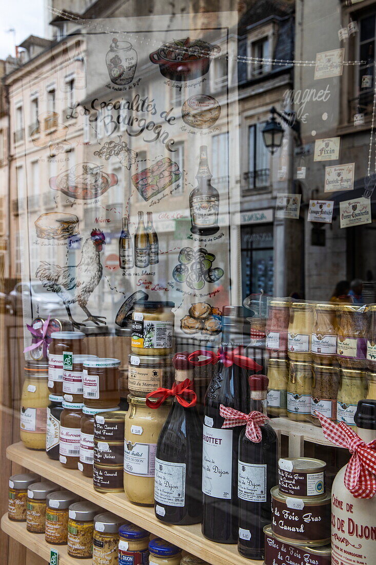 Reflection in the window and various varieties of Dijon mustard and other local specialties for sale in a delicatessen, Beaune, Côte-d'Or, France, Europe