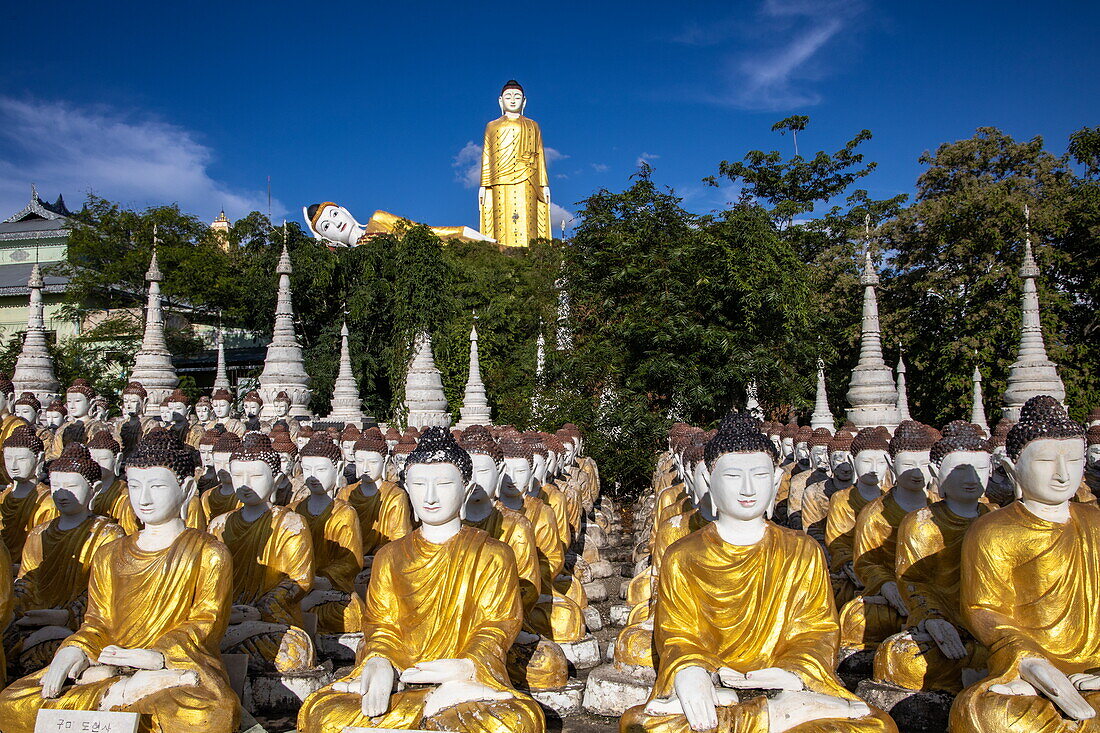 Large number of Buddha statues at Maha Bodhi Tahtaung Monastery with Reclining Buddha and Laykyun Sekkya Standing Buddha Statue behind, Monywa Township, Sagaing Region, Myanmar, Asia