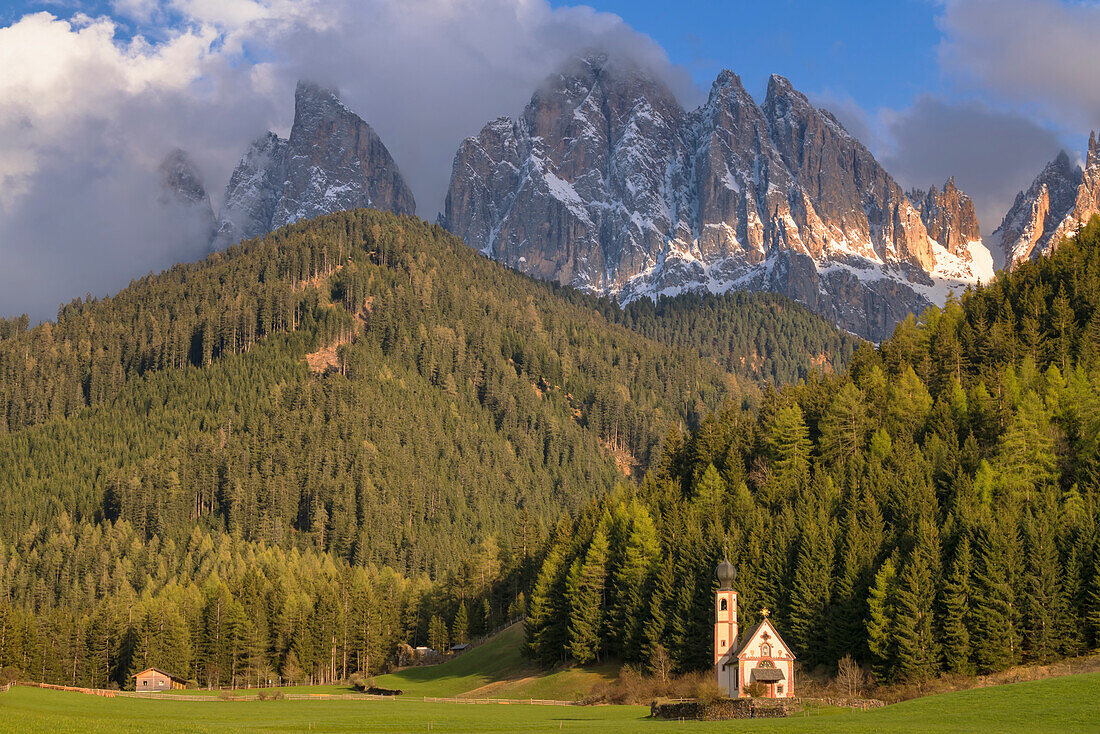 Die Kirche St. Magdalena im Villnösstal, im Hintergrund die Dolomiten, Gipfel der Geislerspitzen, Südtirol, Italien.