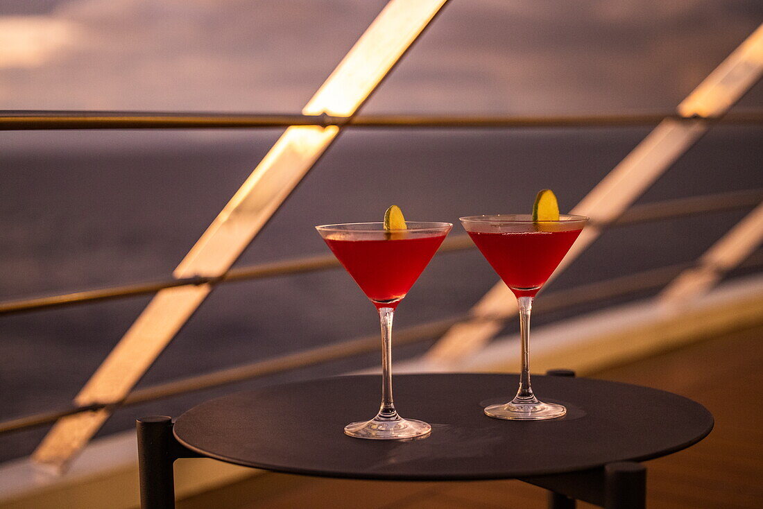 Detail of two cocktail glasses on a deck table aboard expedition cruise ship World Voyager (Nicko Cruises) at sunset, near Puerto Jiménez, Puntarenas, Costa Rica, Central America