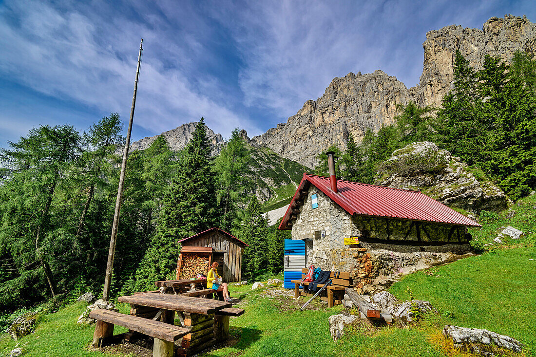 Woman sitting in front of Bivacco Campestrin hut, Bosconero Group, Dolomites, Veneto, Veneto, Italy