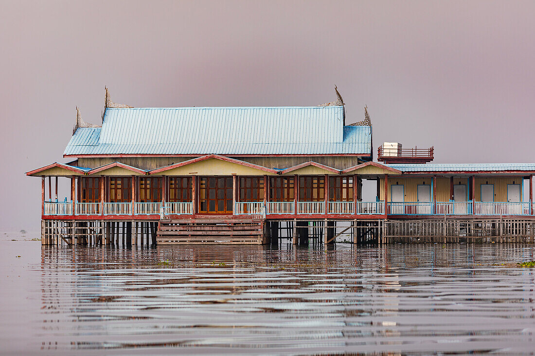 Ein malerisches Stelzenhaus liegt mystisch im burmesischen Inle-See bei Nebel, Shan-Staat, Myanmar