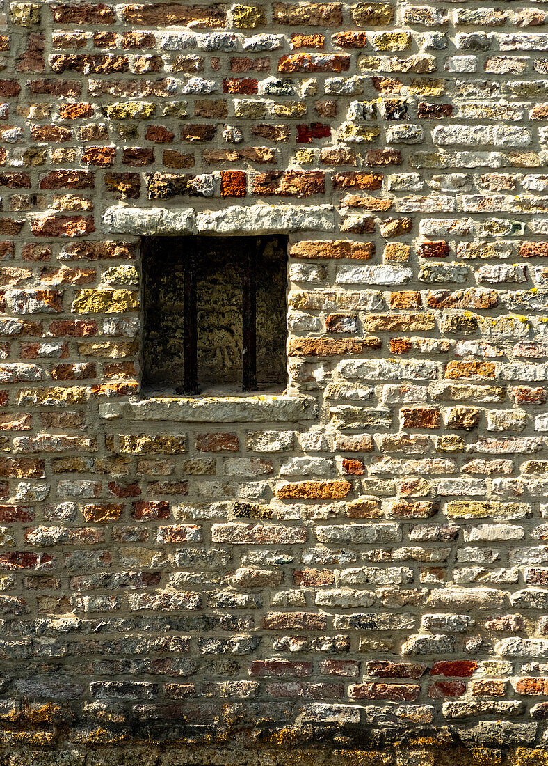 Backsteinmauer mit einer kleinen Öffnung.