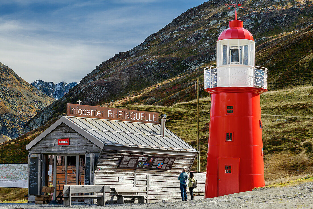 Two people stand in front of the Rheinquelle information center and lighthouse at the Oberalp Pass, Gotthard Group, Graubünden, Switzerland