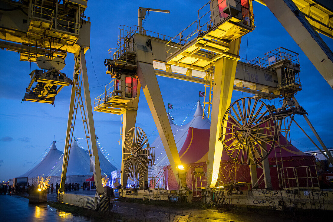 Ausgestellte Containerkräne neben Zirkuszelten auf dem Wintervuur-Festival in Antwerpen, Flandern, Belgien