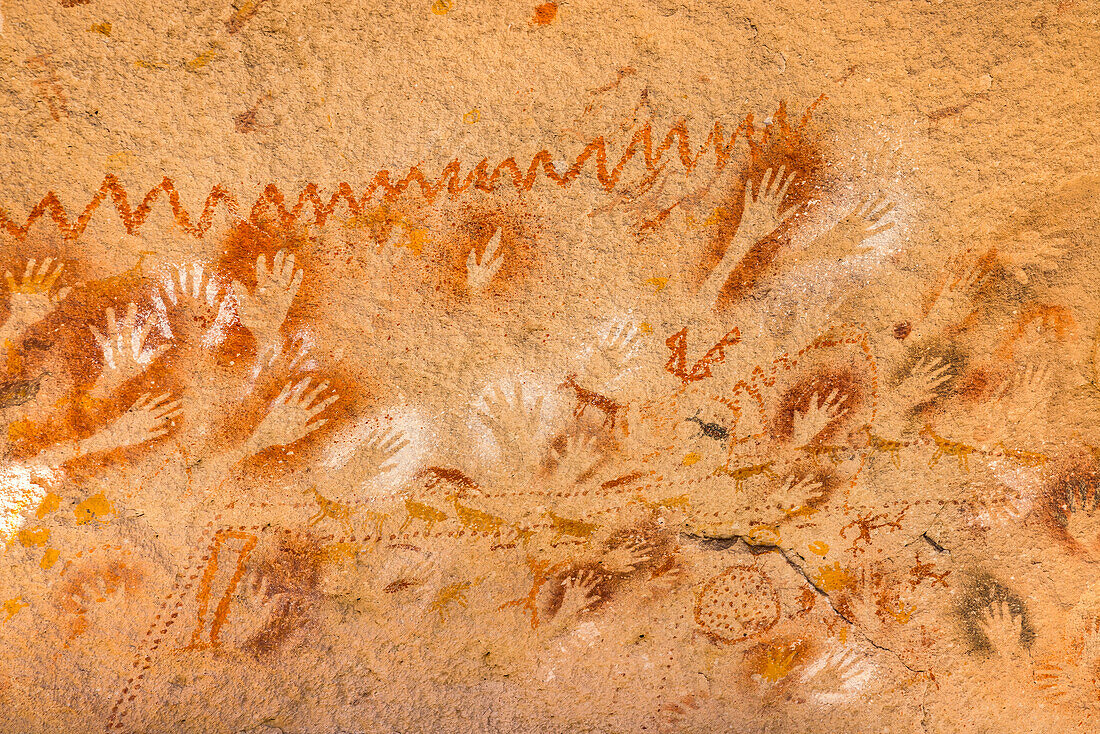 Antike Höhlenmalereien mit Jagdzene, Menschen, Tiere und Hände auf einer Felswand am Weltkulturerbe Cueva de las Manos, Argentinien, Patagonien