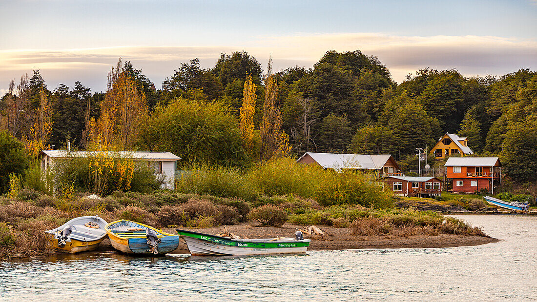 Boote und Häuser am Strand der idyllischen Kleinstadt Puerto Rio Tranquilo am Lago General Carrera in Chile bei Sonnenuntergang, Patagonien, Südamerika