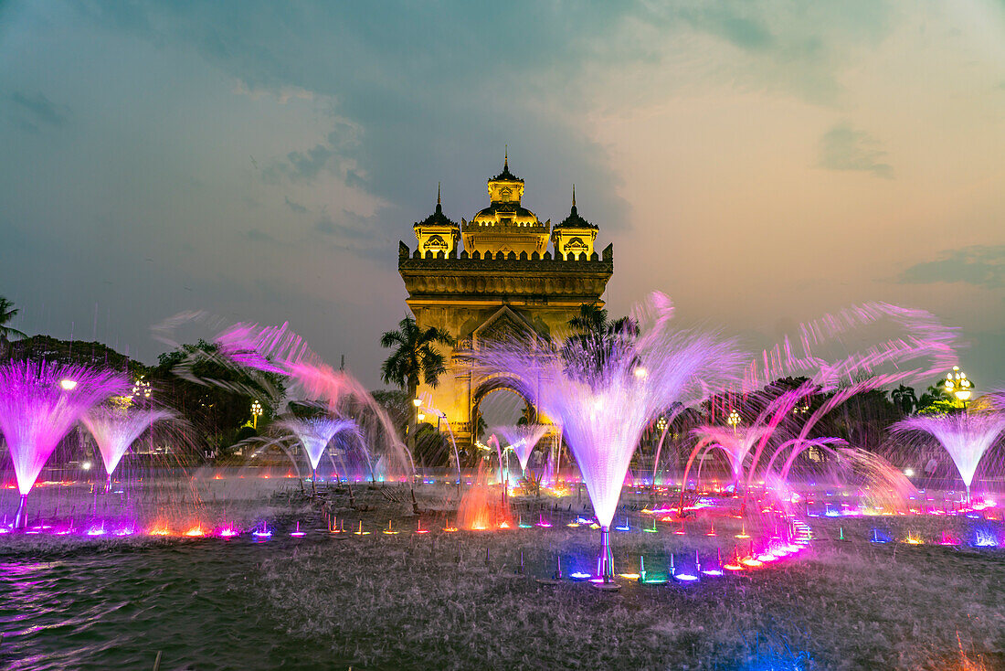 Bunt beleuchteter Brunnen am Siegestor Patuxai in der Abenddämmerung, Hauptstadt Vientiane, Laos, Asien