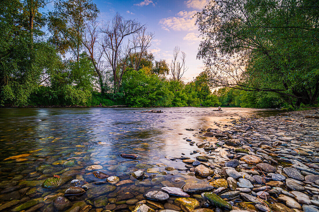 Langzeitbelichtung am steinigen Ufer vom Fluss Saale im Sommer bei Sonnenuntergang und blauem Himmel, Jena, Thüringen, Deutschland