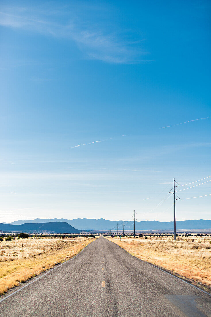 Straße, die sich in eine Prärielandschaft erstreckt, New Mexico, USA