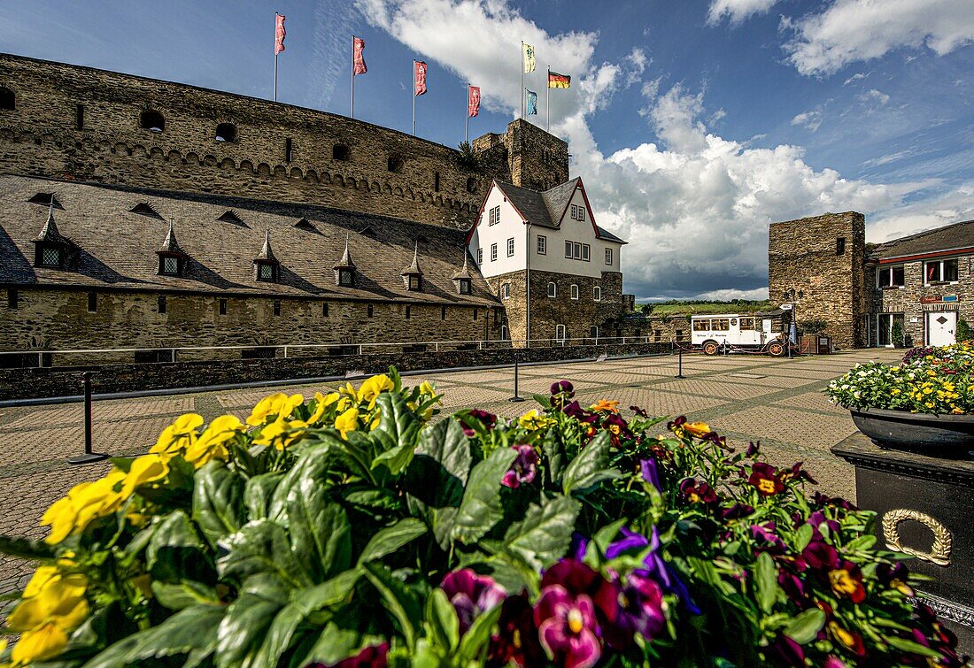 View over the flower-decorated courtyard of Hotel Schloss Rheinfels and onto the outer bailey and entrance area of Rheinfels Castle, St. Goar, Upper Middle Rhine Valley, Rhineland-Palatinate, Germany