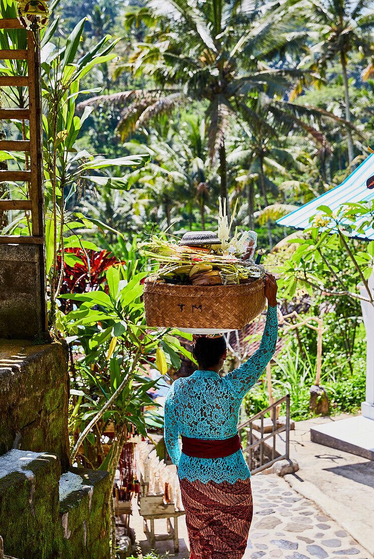 Eine balinesische Frau in traditioneller Kleidung trägt Opfergaben zu einem Gottesdienst in Gunung Kawi, Gianyar, Bali Indonesien